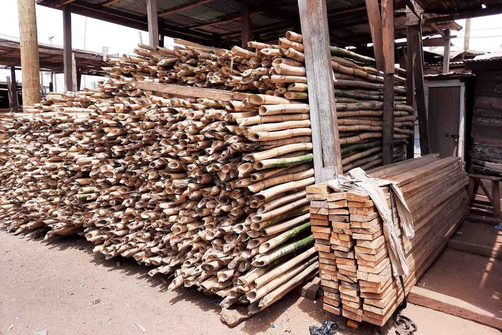 Stacks of bamboo and sawn timber planks under an open-air shelter.