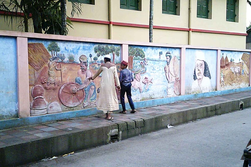 Murals painted on wall next to tiled pavement.