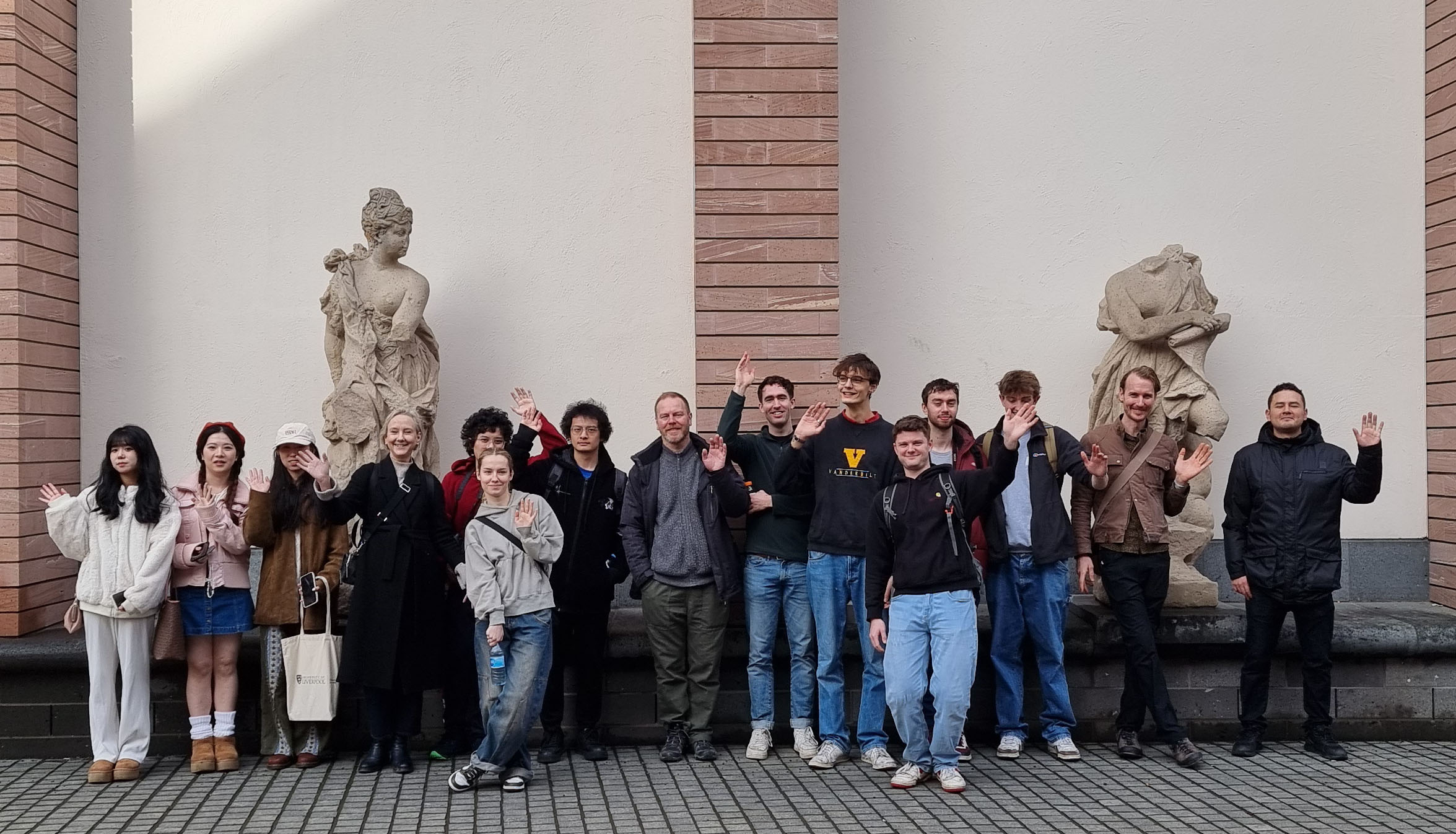 Group of students standing in front of clasical sculpture in a museum.