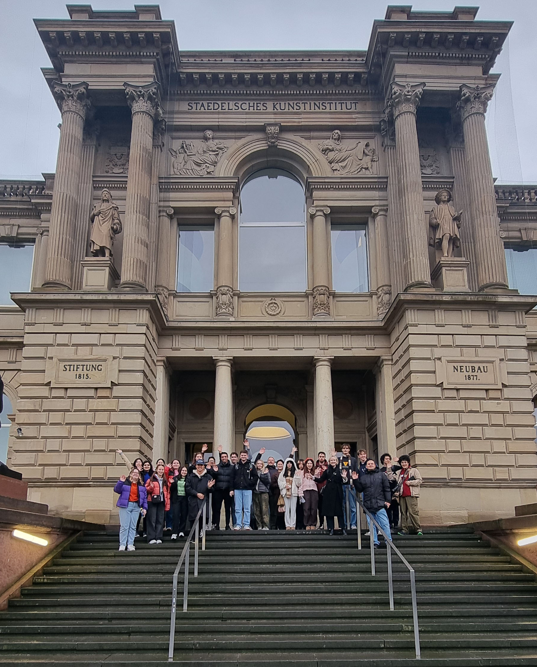 Group of students standing in front of a clasical facade to a museum.