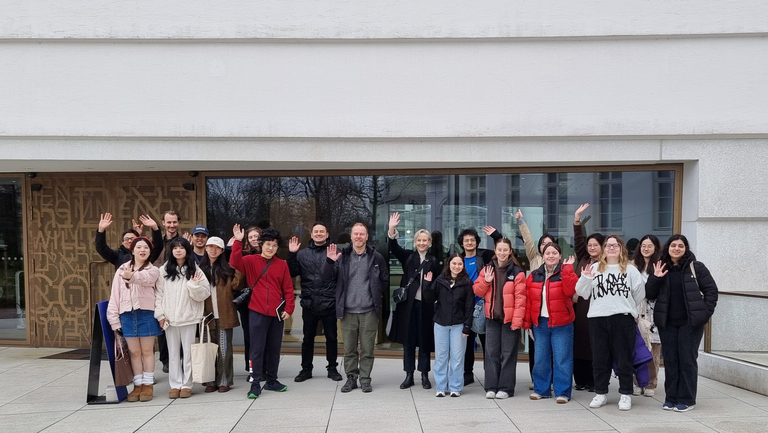 Group of students standing outside a glass and concrete facade of a museum